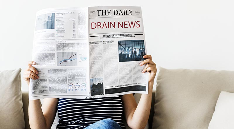 woman holding a newspaper with the headline drain news